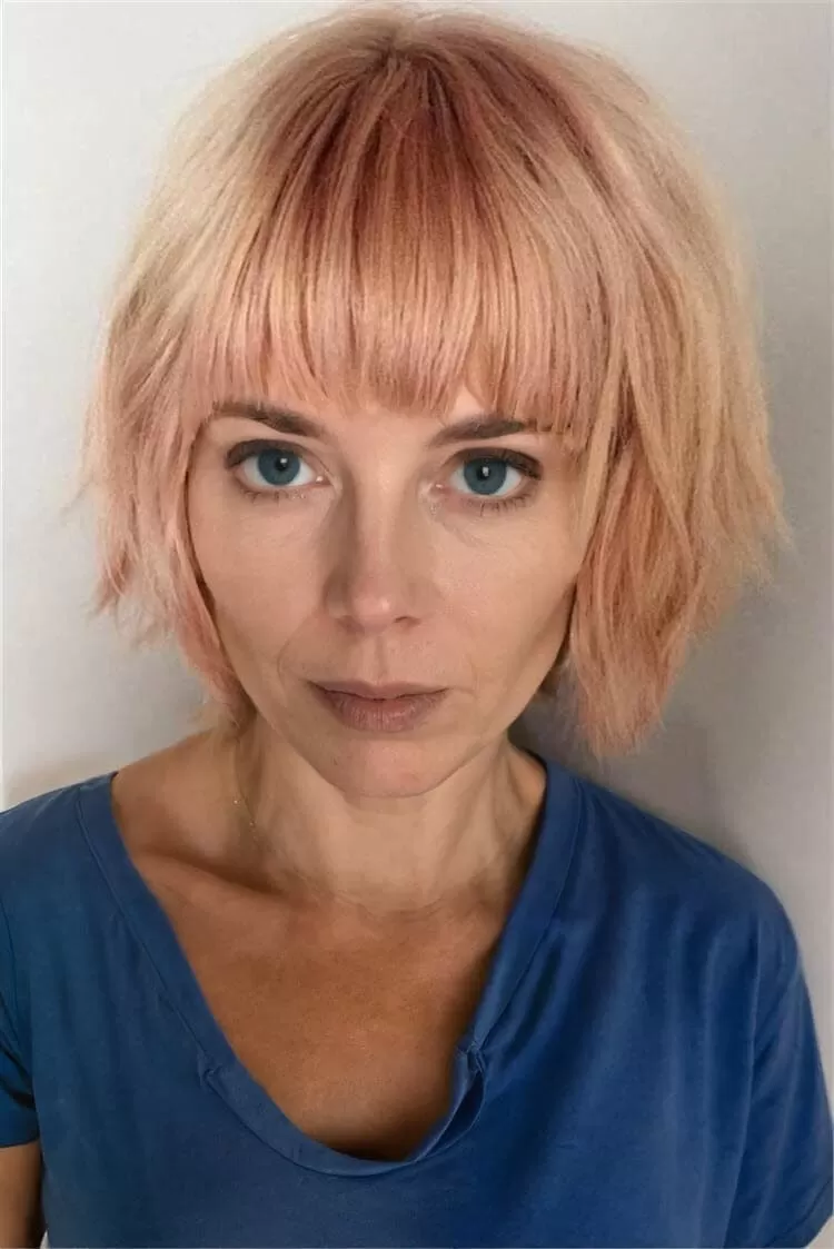 Stilvolle Bob Frisur mit geradem Pony in Pastellrosa, ideal für verschiedene Gesichtsformen